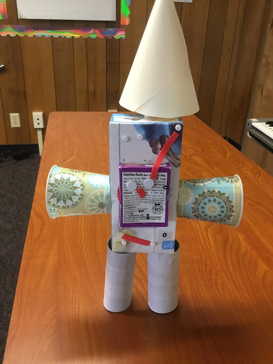 Robot created by two boys with paper cups, toilet paper rolls, and other scraps