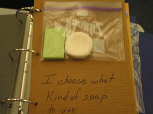 Page from an object book with two bars of soap in a baggie and the text “I choose what kind of soap to use.”