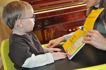 Young boy with glasses looks at picture book.