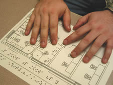 Photo of two hands exploring a page of tactile graphics