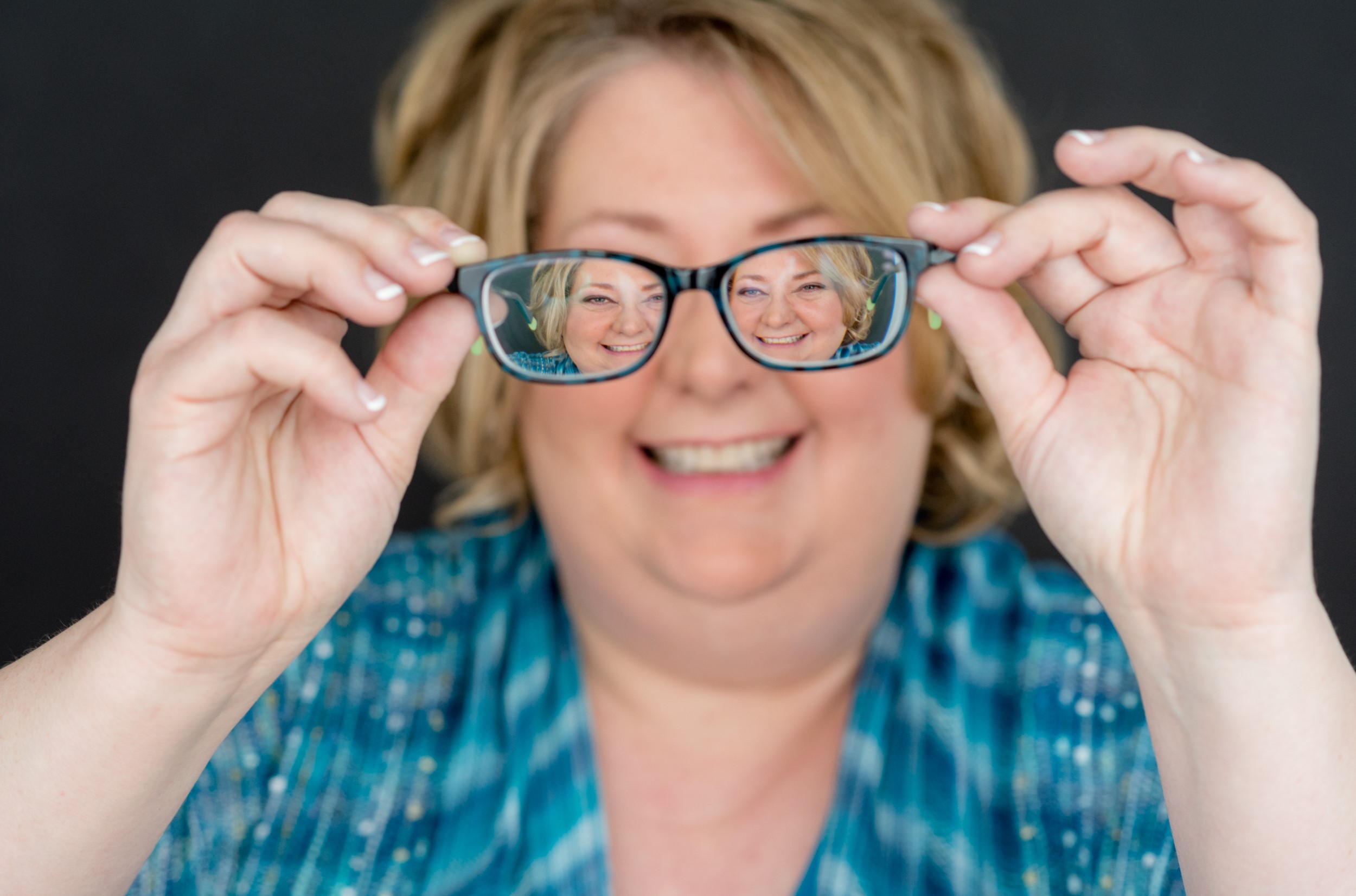 Stehanie Duesing holding her glasses infron of her face.