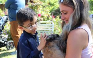 Student petting a bunny that is being held by an adult.