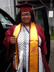 Jasmyn in her cap and gown, with her cane in hand, graduating from Kutztown University. 