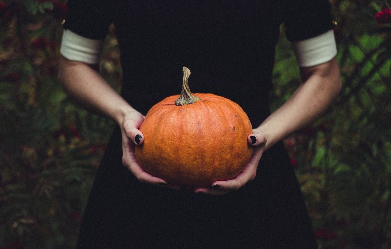 A woman holding a small pumpkin