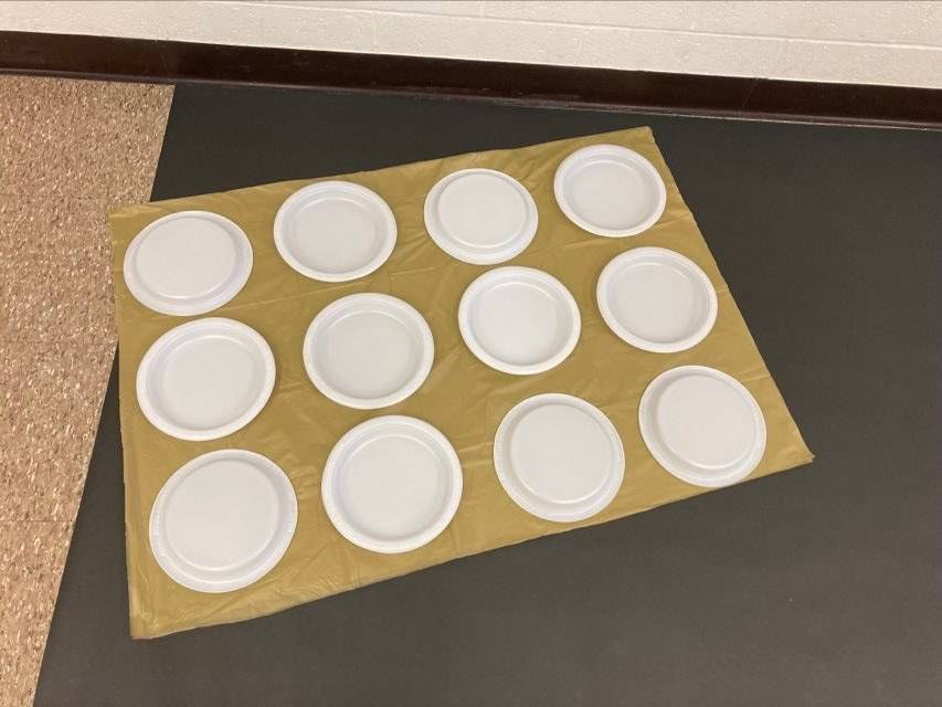 Plates are aligned on a gold table cloth to represent braille cells.