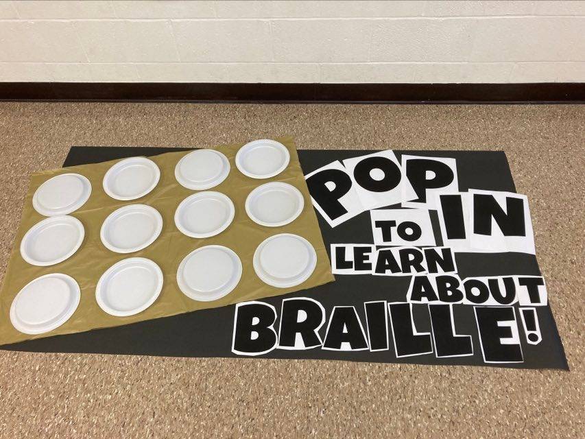 Sign for the bulletin board that says, "Pop in to learn about braille!" with the plates representing braille.