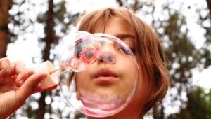 A girl outside blowing bubbles.