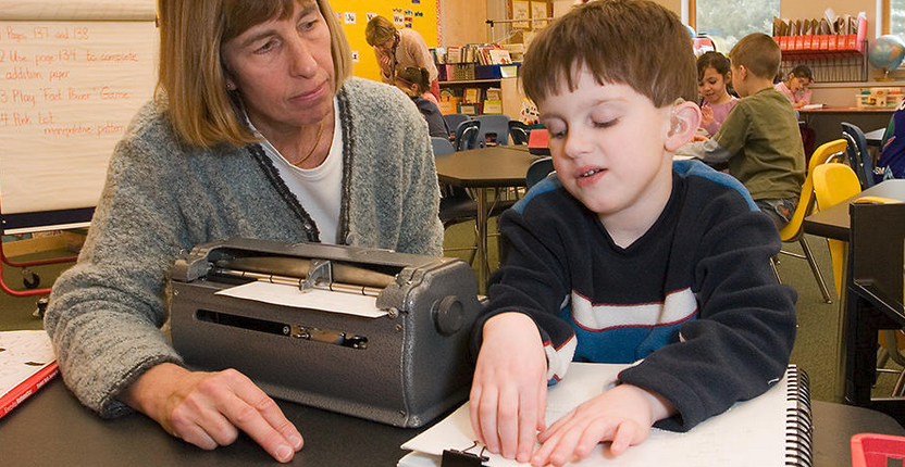 Student at a braille machine with his instructor.