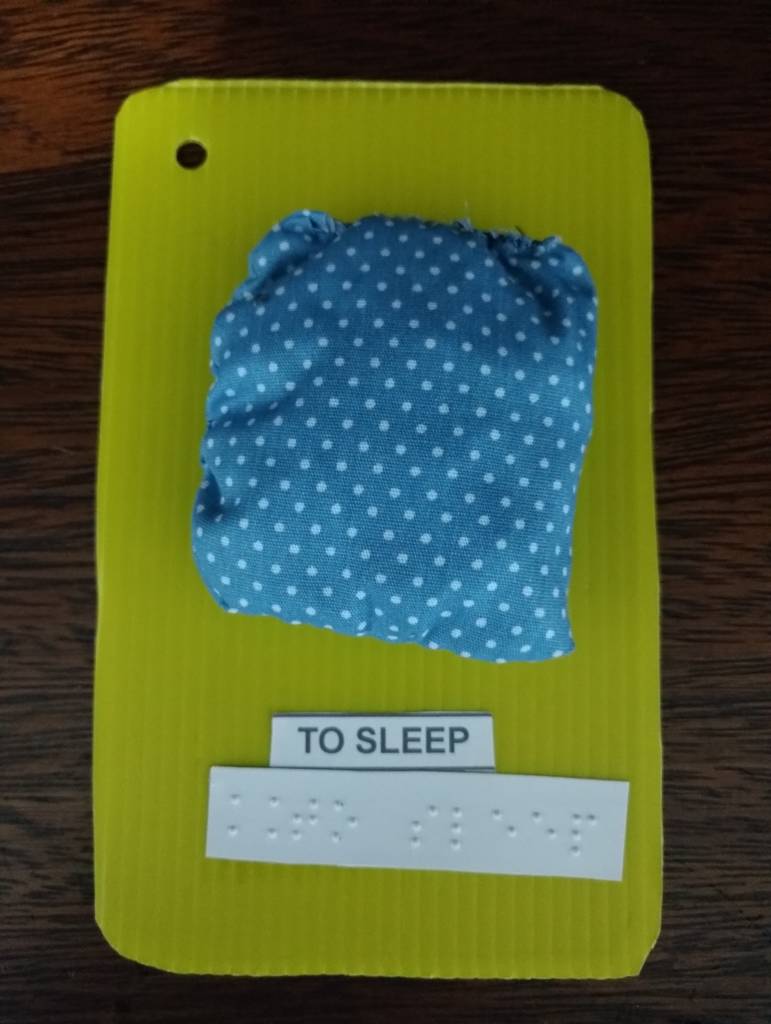 Color image. Under a wooden background, a small pillow that
represents “sleep”.