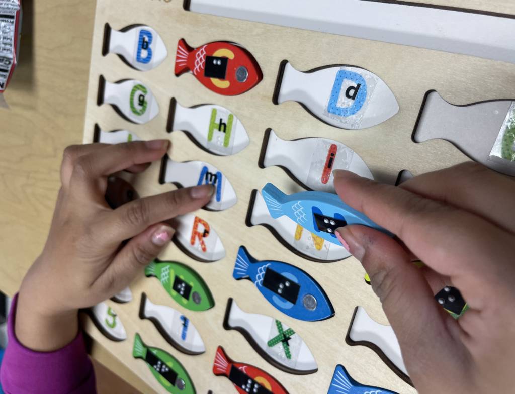 Student putting puzzle pieces in by matching the braille letters and numbers.