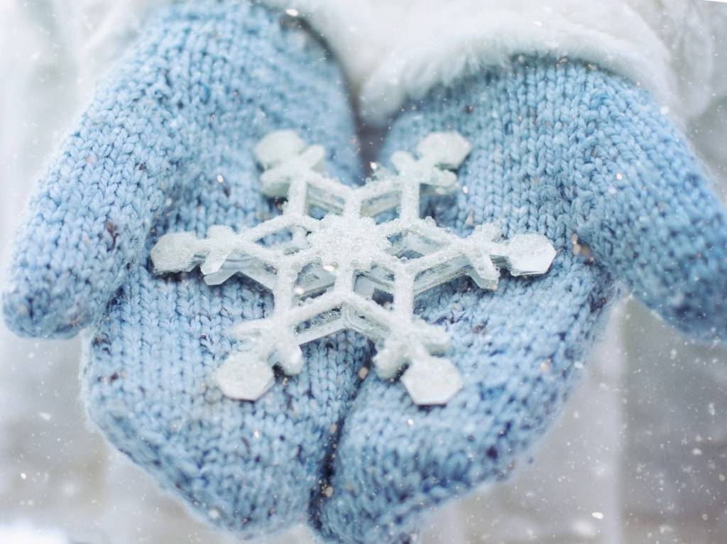 Hand with mittens holding a large snowflake