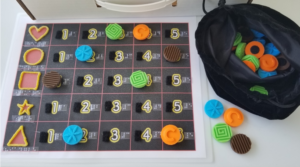 Made game board with raised lined shapes, numbers, and 3-D game pieces.