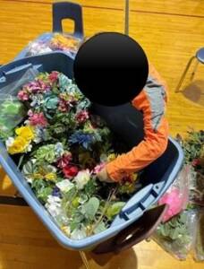 Student finding silk flowers in a container.