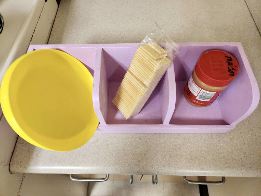 A plate, sleeve of crackers, and jar of peanut butter in a 3-slot sequence box.