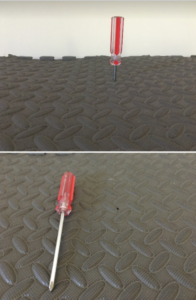 Screwdriver poking a hole in a mat.