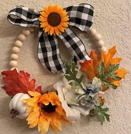 Wreath with beads and autumn silk flowers and leaves plus a ribbon and a mini pumpkin. 