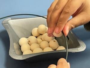 Hands on a metal wire circle putting on wood beads to make a wreath