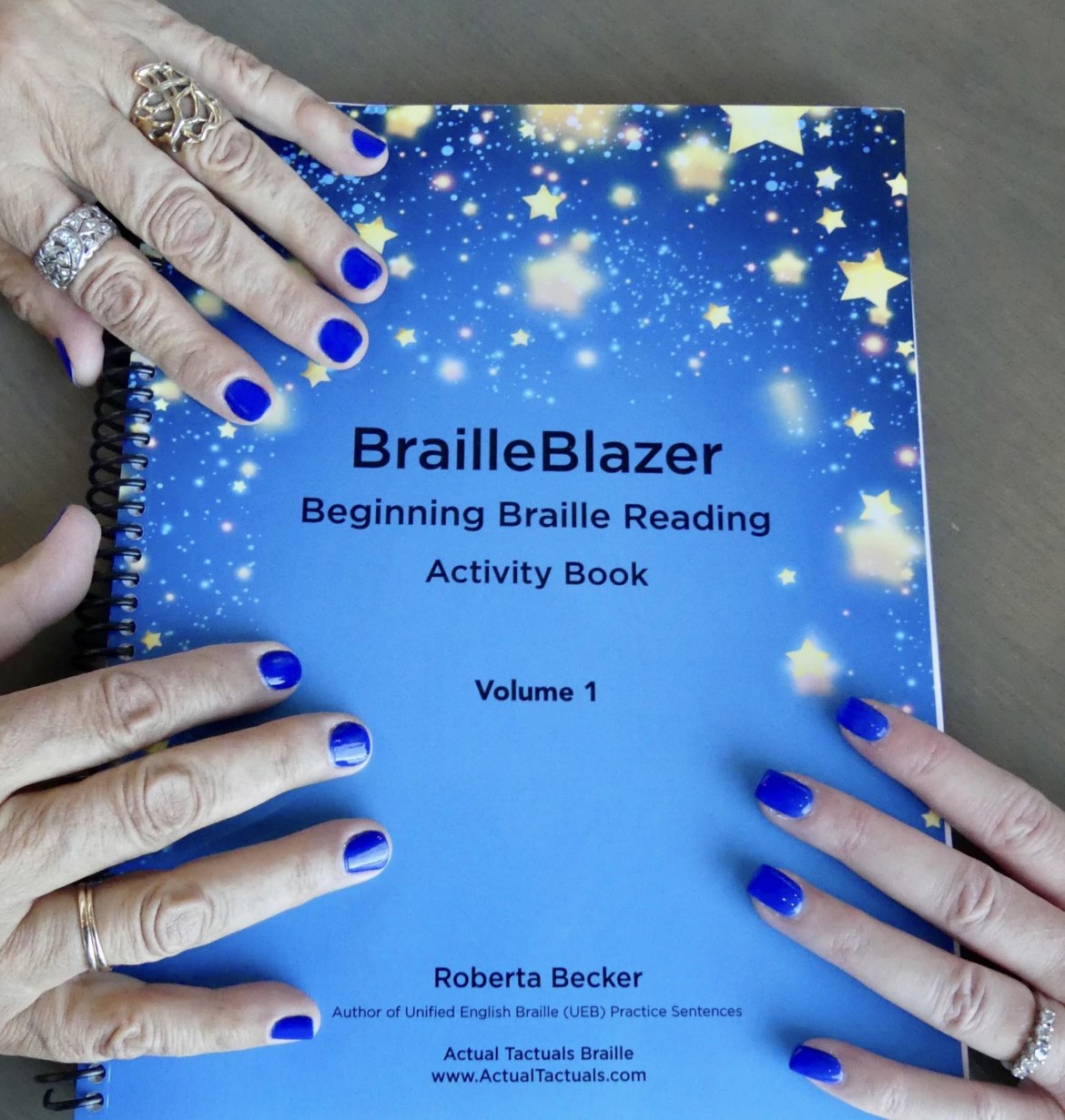 Cover of the BrailleBlazer book with hands on the book.