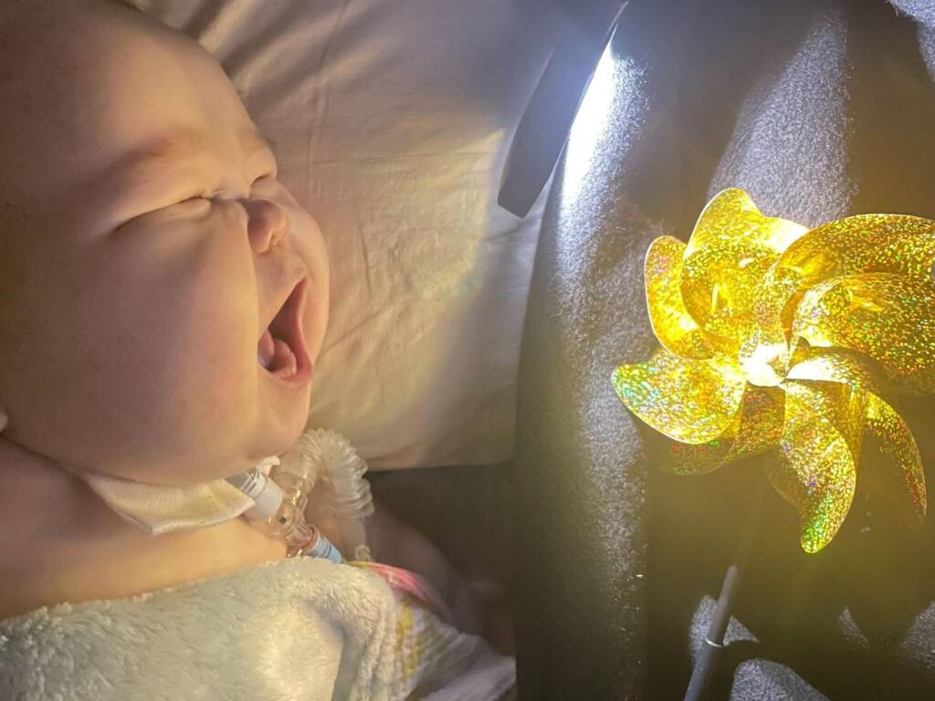 Young child excited with their mouth open while looking at a golden metallic pinwheel