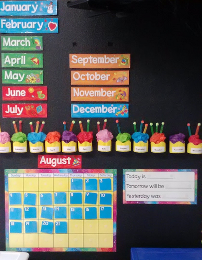 Calendar bulletin board with simple, high contrast colors. Monthly calendar and paper cupcakes for each month with candles for each students birthday