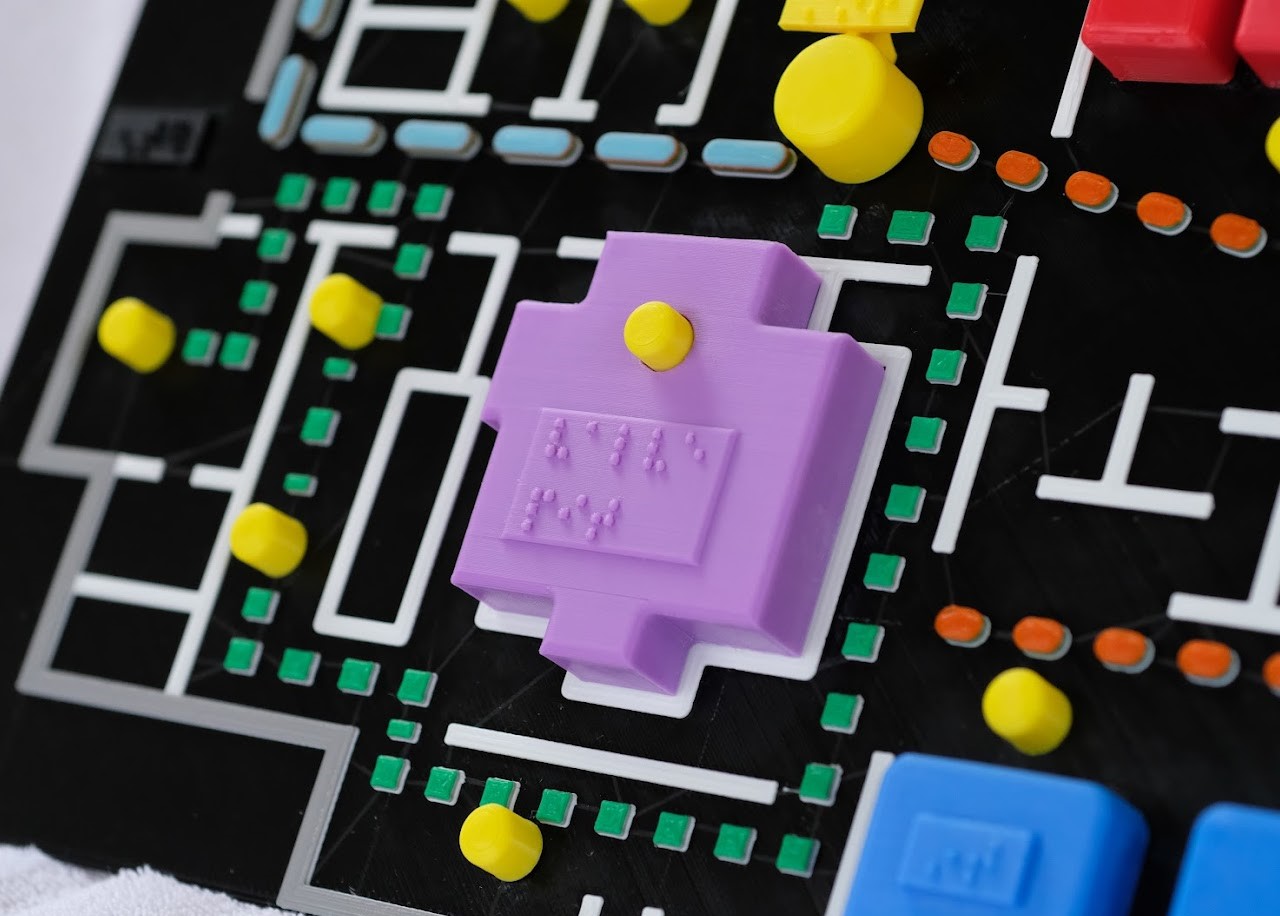 Up close photo of a high-contrast, 3D printed tactile map with braille labels various paths of travel.