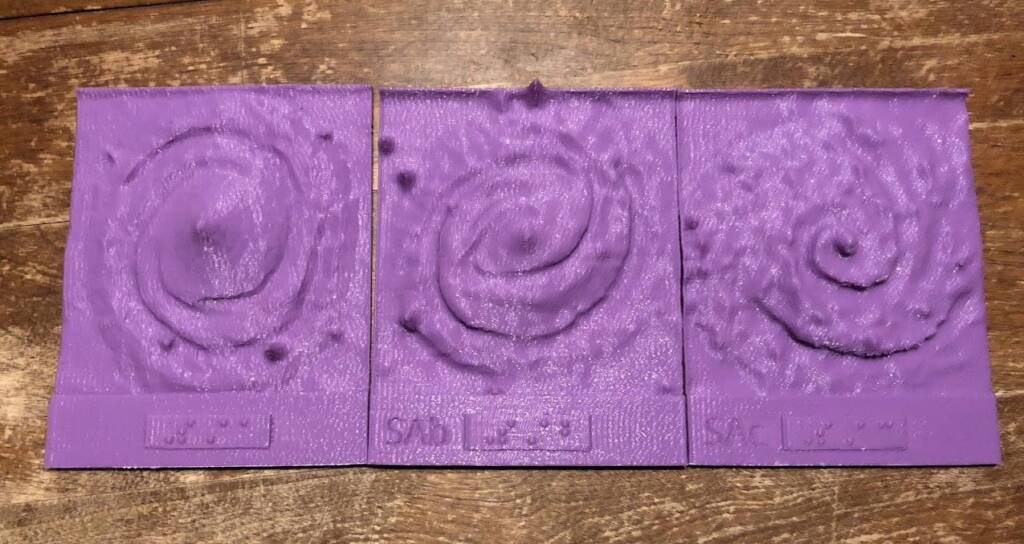 3D printed tactile graphics of 3 spiral arm galaxies with braille and print labels