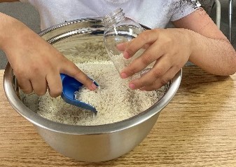 Student scooping rice and filling them into a bottle.