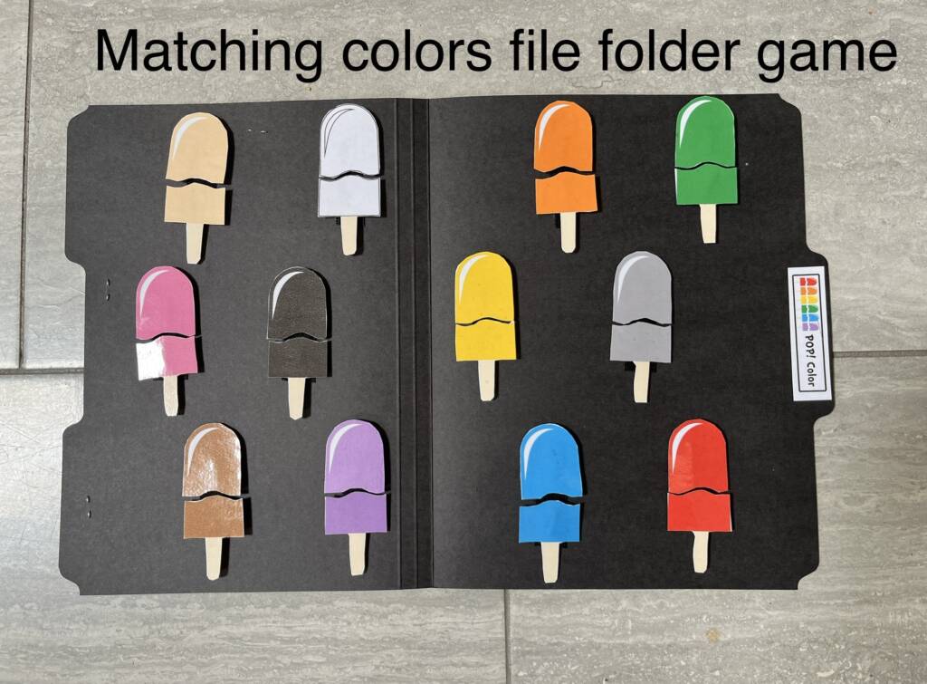Different colored paper popsicles within a black file folder. Each popsicle is divided into two pieces. Text "Matching colors file folder game"