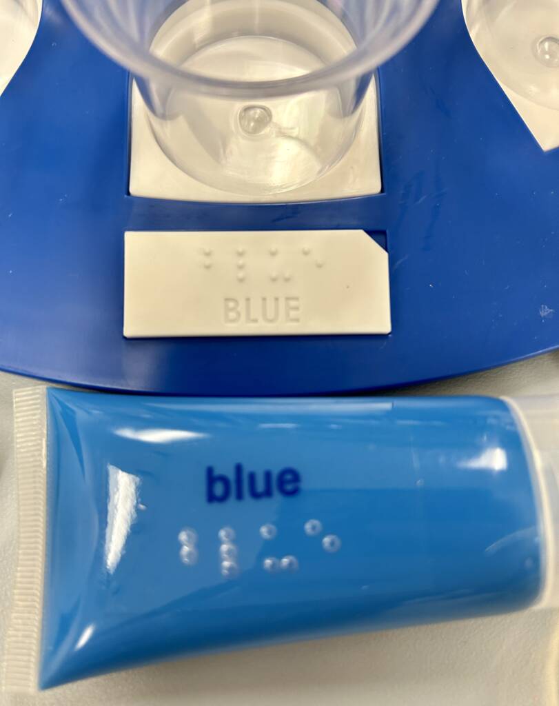 Pictured is the paint tray and tube of paint with the word "blue" on them in both print and braille.