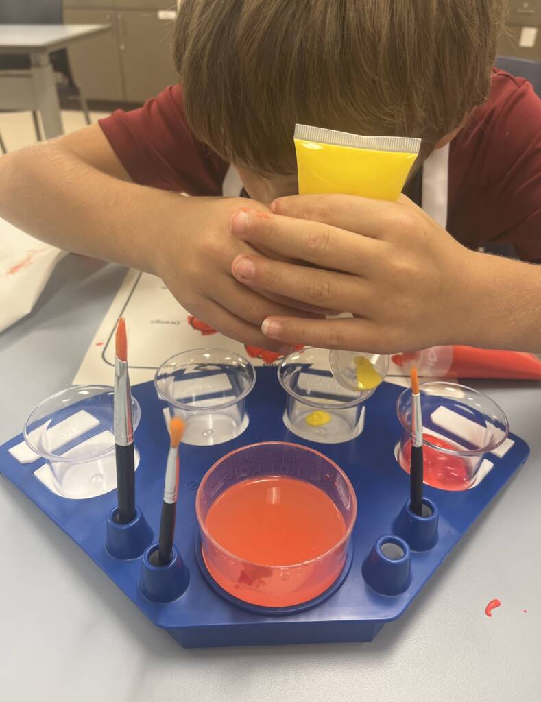 Student is squeezing paint out of the paint tube into a cup