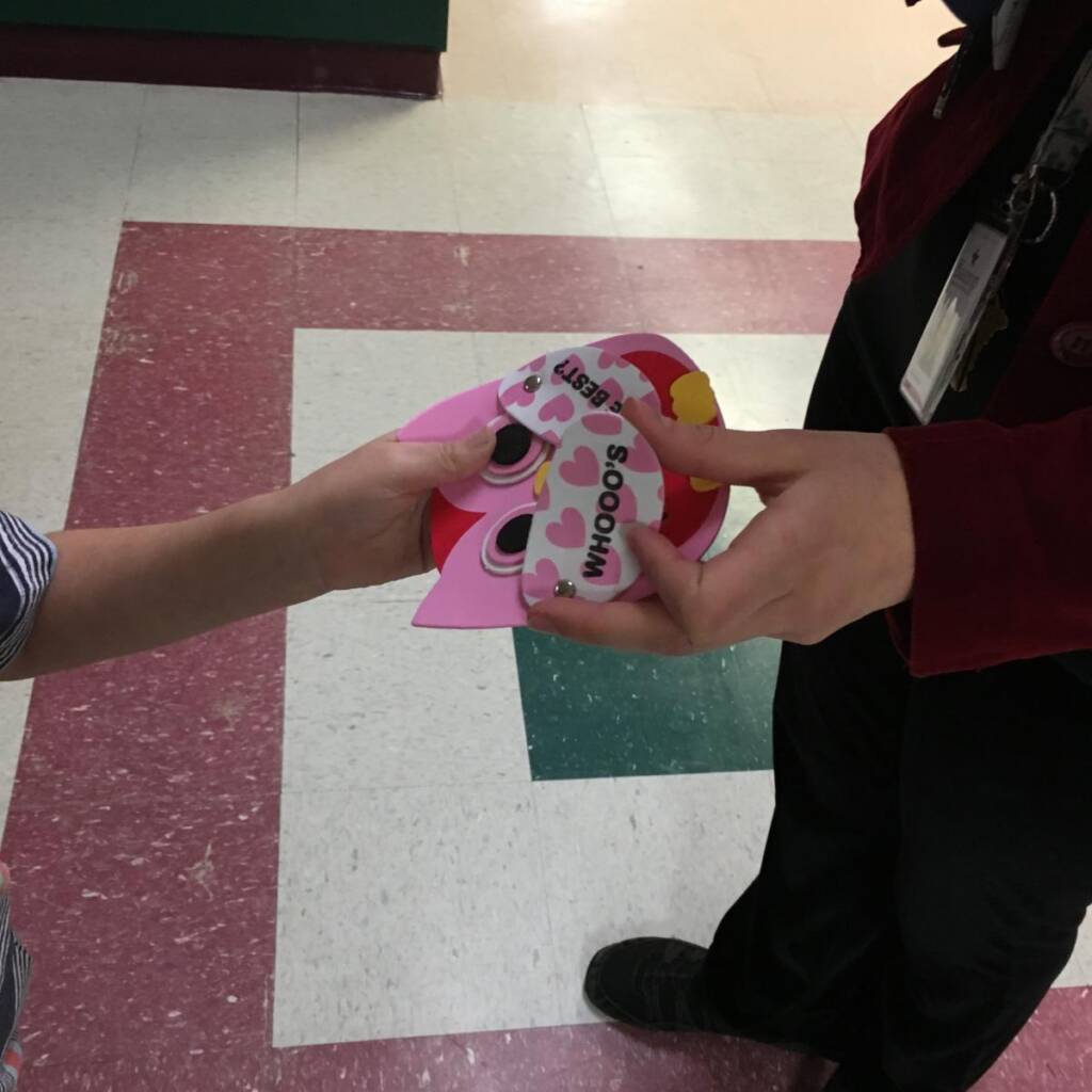 A student hands a valentine to an adult