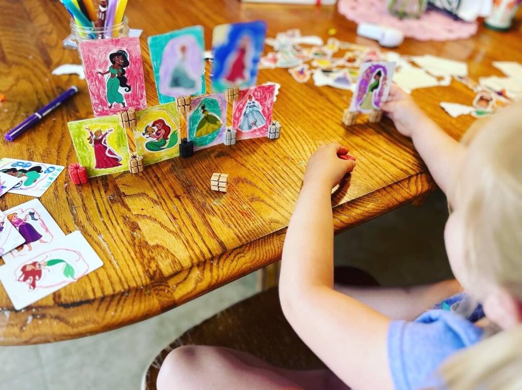 Little girl playing with disney princess cards and using the Ti'TAINS to keep them upright.