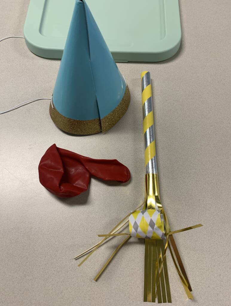 Paper hat, balloon, and a paper blow horn.