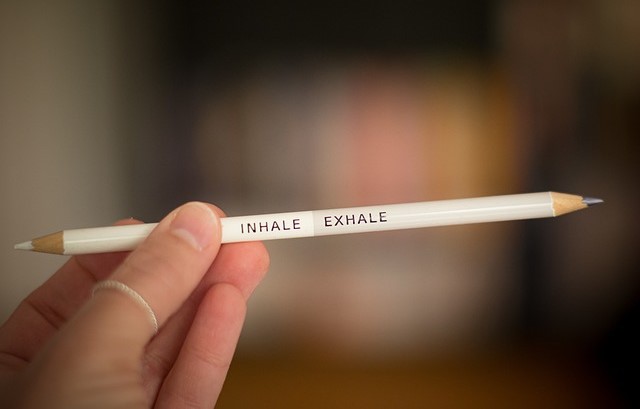 Hand holding a pencil that says, "inhale, exhale".