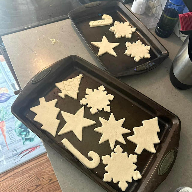 Various winter and Christmas shaped salt dough pieces placed on a baking sheets.