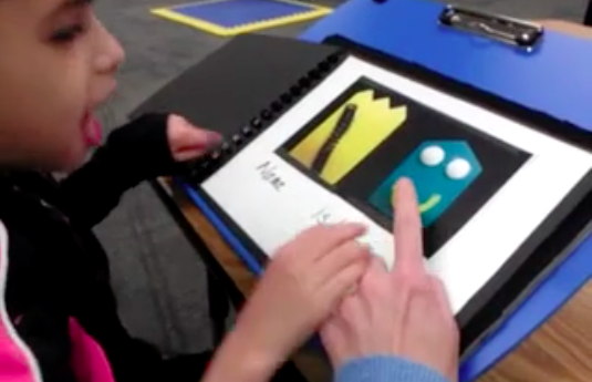 A girl reads a book using the symbol system.