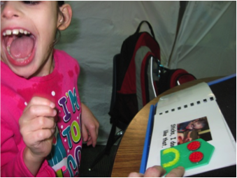 Click to view The same student, laughing with excitement, at being able to interpret the 3-D symbol in her book for “sad”