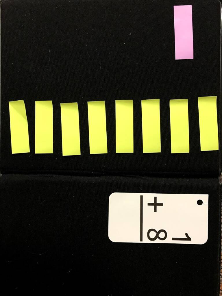 One pink post it note and 8 yellow post it notes are next to a flashcard with the math problem "1+8".