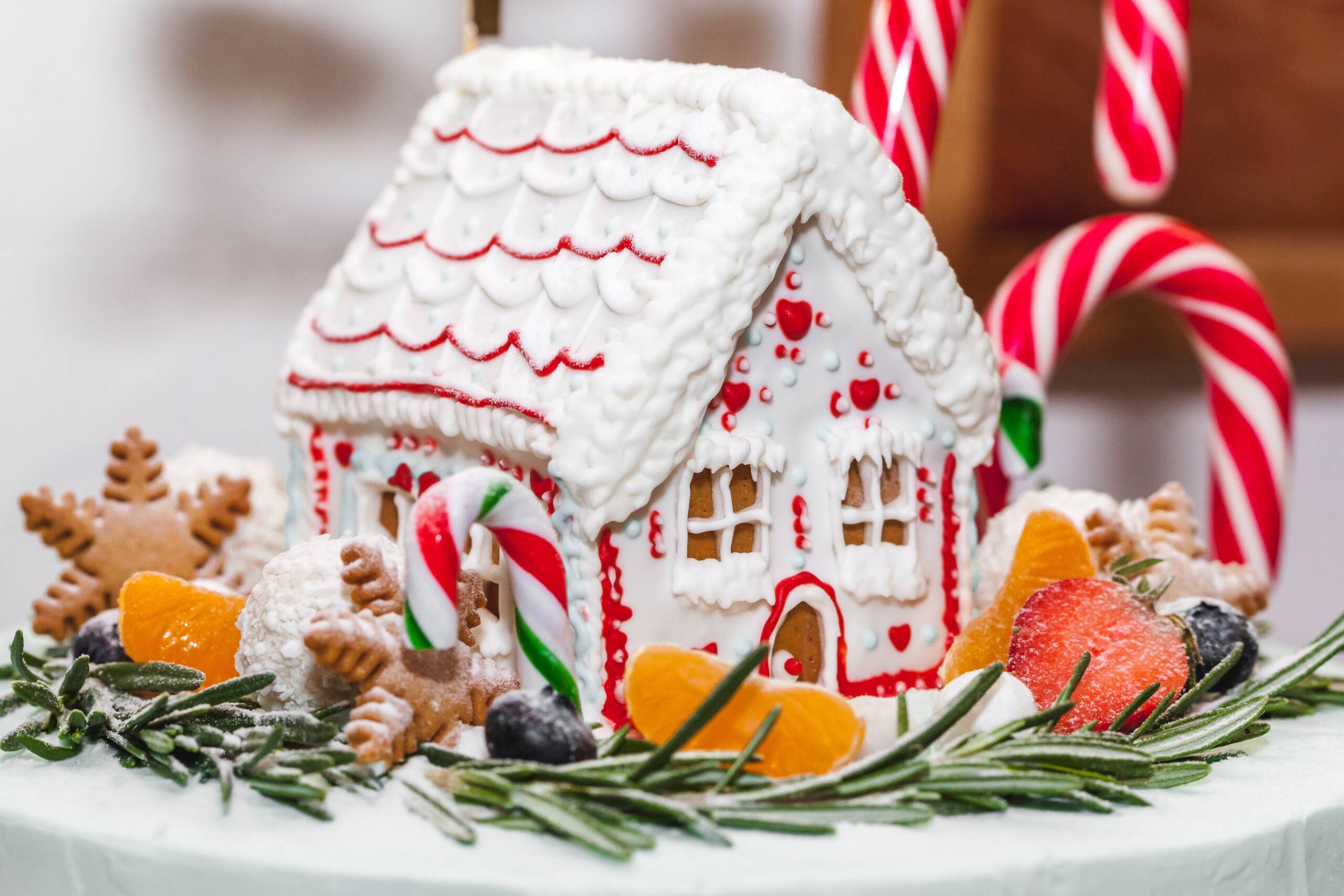 A gingerbread house sitting on a table surrounded by greenery