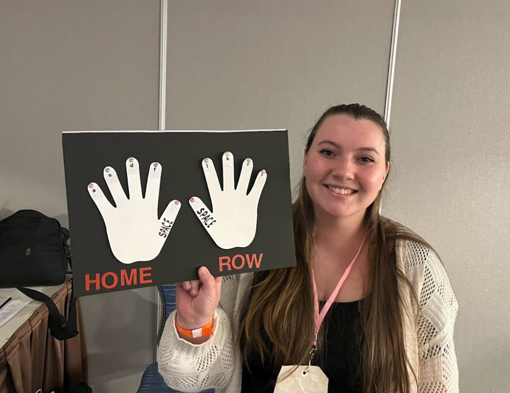 Kutztown U. student with her make and take that is a small poster board of two hands with with the Home Row keys for typing.