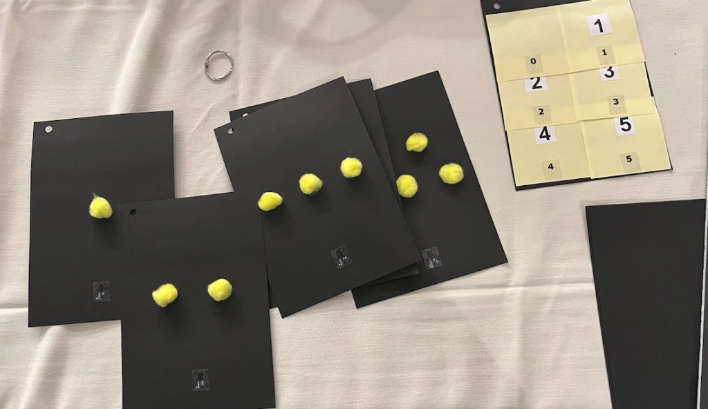 A flip book with pom-pom balls used at objects for counting 0 to 5.