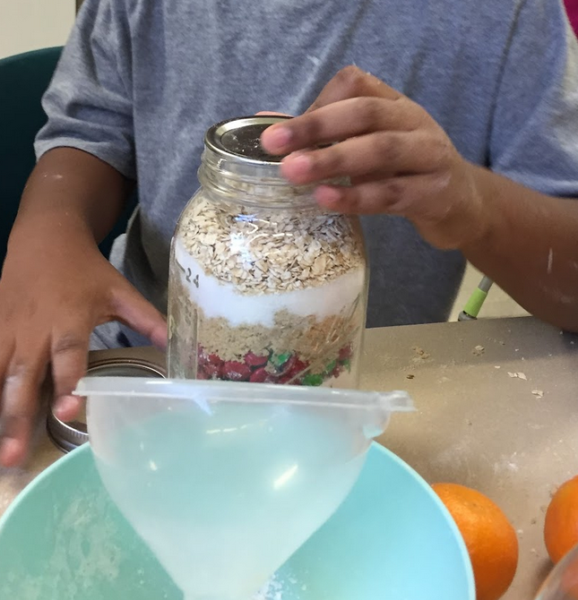 A student securing the lid to the mason jar filled with cookie ingredients