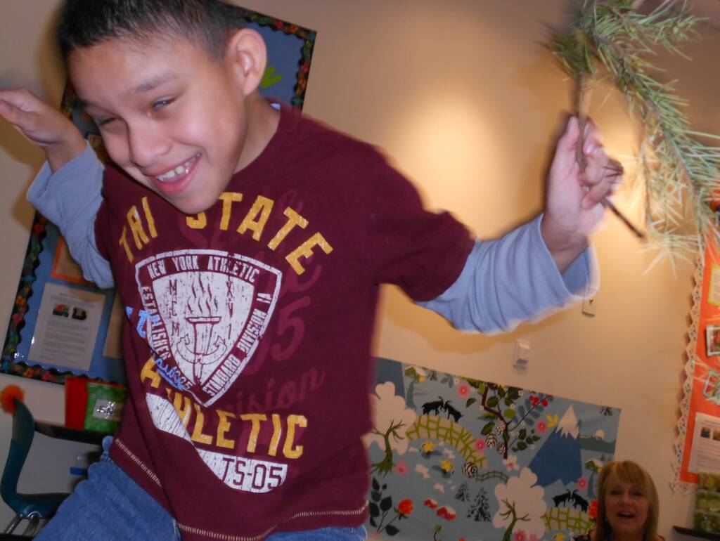 Pinetree dance, student dancing while holding a pine branch.