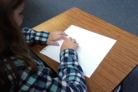 A girl reading a page of braille