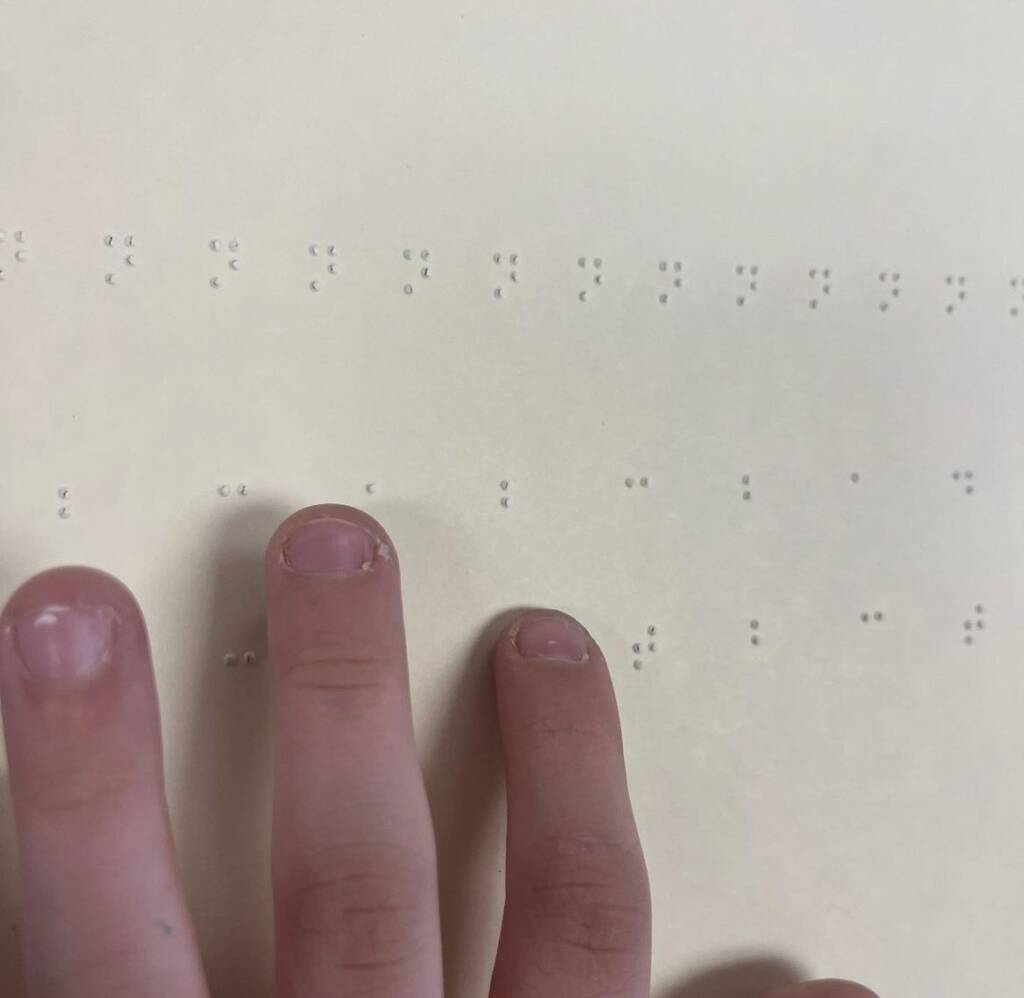 Student using their index finger to touch a line of braille