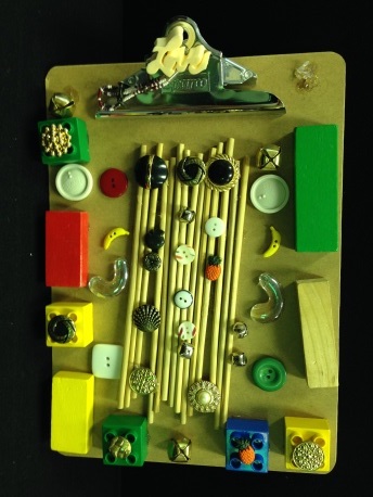 Tactile clipboard with wooden sticks, buttons, wooden blocks and other materials