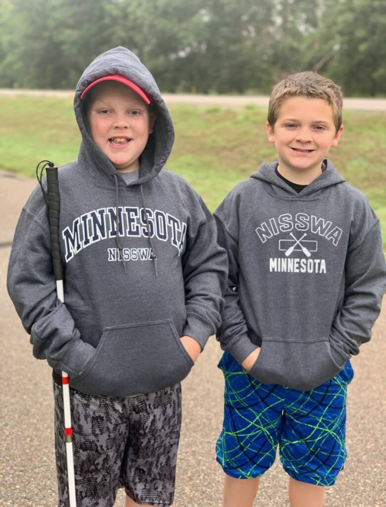 Liam and his brother outside, he is holding his cane.