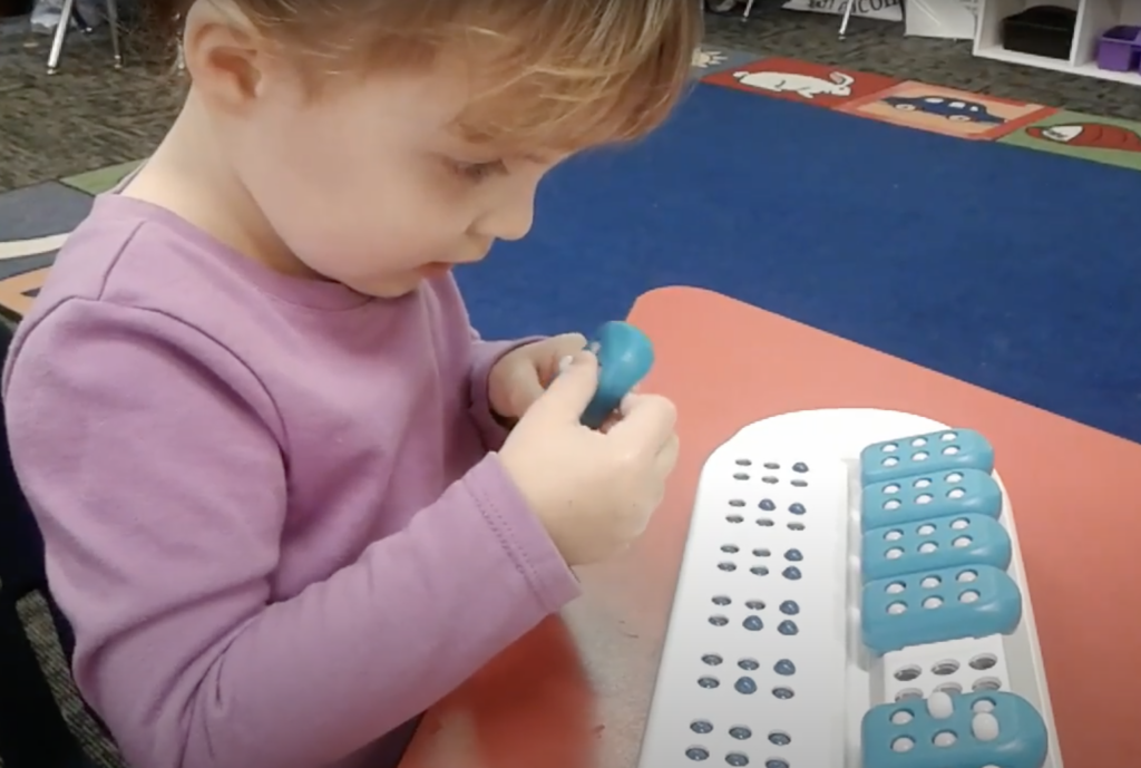 A young girl using Taptilo Braille Learner