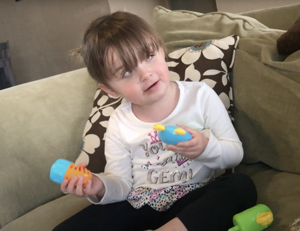 A young girl plays with a pop toy.