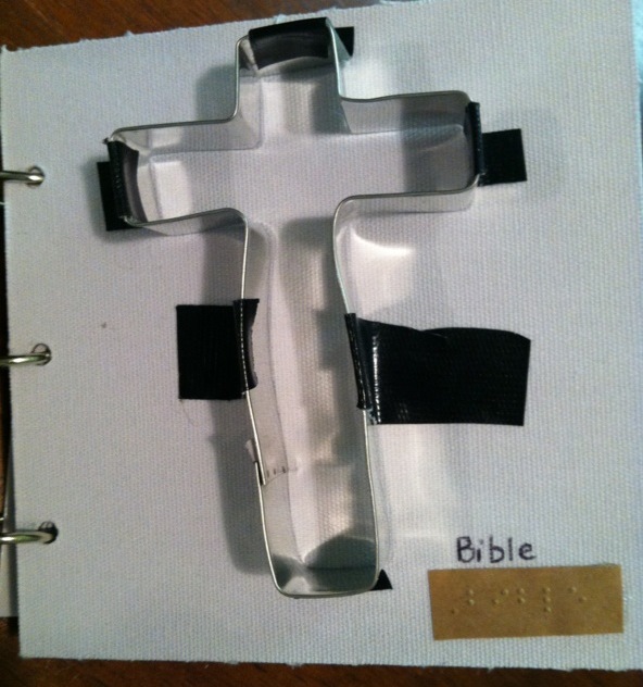 Metal cross with text in print and braille "Bible"